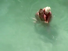 Busty blonde nudist swimming in the water